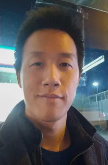 A close-up shot of an asian man looking seriously into the camera lens.