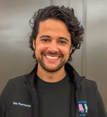 A smiling man wearing a vest that says "pediatrics"