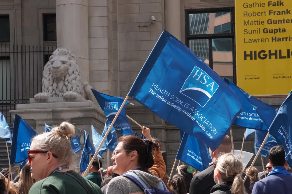 A flag showing HSA's logo and slogan flies in front of the Vancouver Art Gallery.